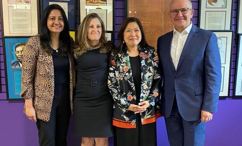 Group of four professionals posing together in front of purple wall with framed portraits, smiling for the camera.