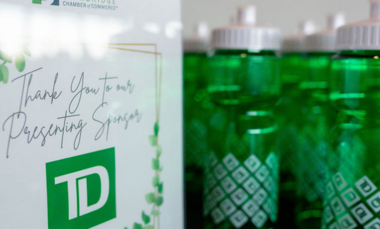 Promotional display with Lethbridge Chamber of Commerce card and TD logo beside green water bottles in the background.