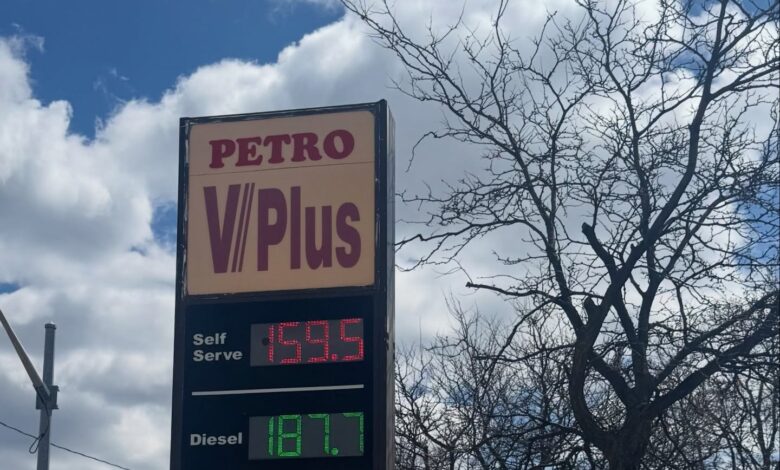 Petro V/Plus fuel sign with self-serve price 159.5 and diesel 187.7, under a cloudy blue sky with bare tree branches nearby.