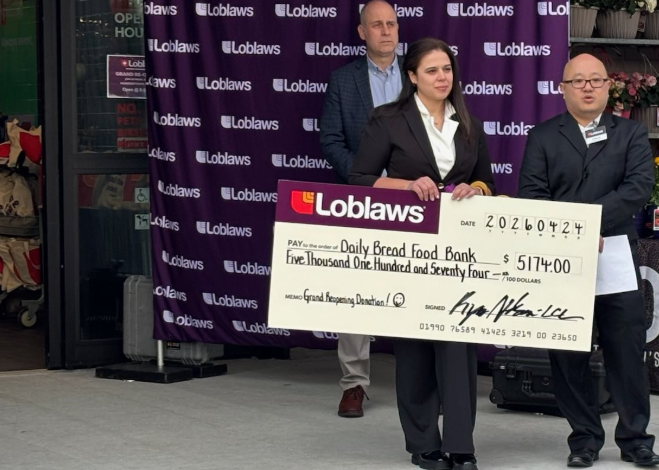 Three people in business attire hold a large ceremonial check from Loblaws to Daily Bread Food Bank for $5,174, standing in front of a purple Loblaws backdrop.