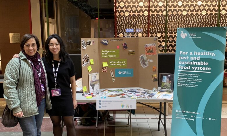 Two women stand side by side at a conference booth with a folding display and FSC banner in the background.