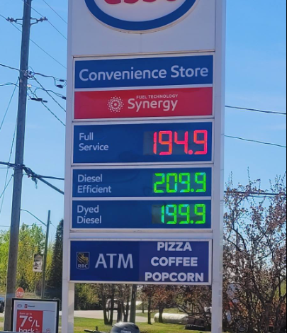 Esso convenience-store sign with Synergy fuel info and prices: full service 194.9, diesel 209.9, dyed diesel 199.9; ATM and pizza/coffee/popcorn notice.