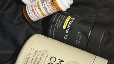 Assortment of dietary supplement bottles on dark fabric, including Multi-Collagen and Vitamin K2 pills as visible labels.