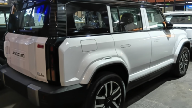 White SUV with black roof rack/roof trim and large multi-spoke alloy wheels, displayed indoors at a car showroom desinged for sale