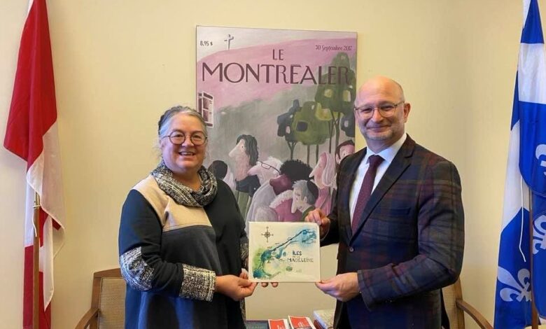 Two adults exchange a certificate in a formal room; flags flank them and a poster reading 'Le Montréalier' is on the wall behind.